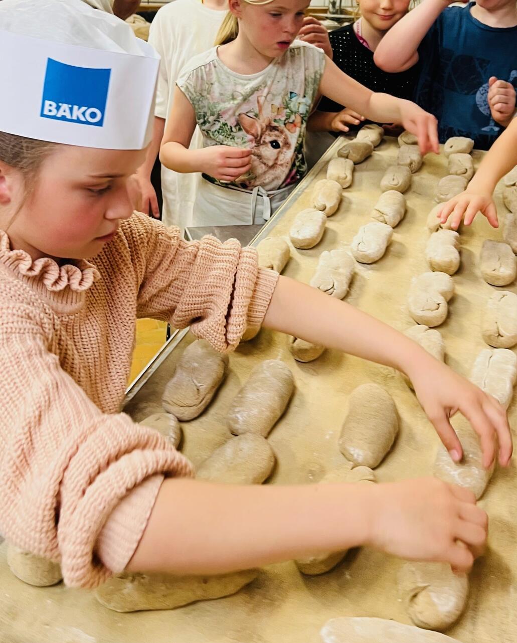 Kinder lernen in der Bäckerei wie Brötchen gebacken werden