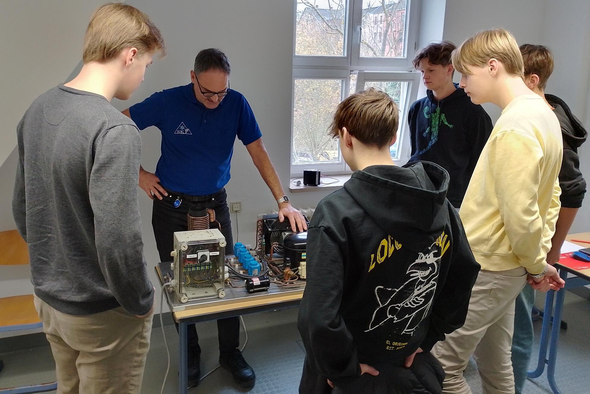 Gymnasiasten betrachten einen technischen Versuchsaufbau