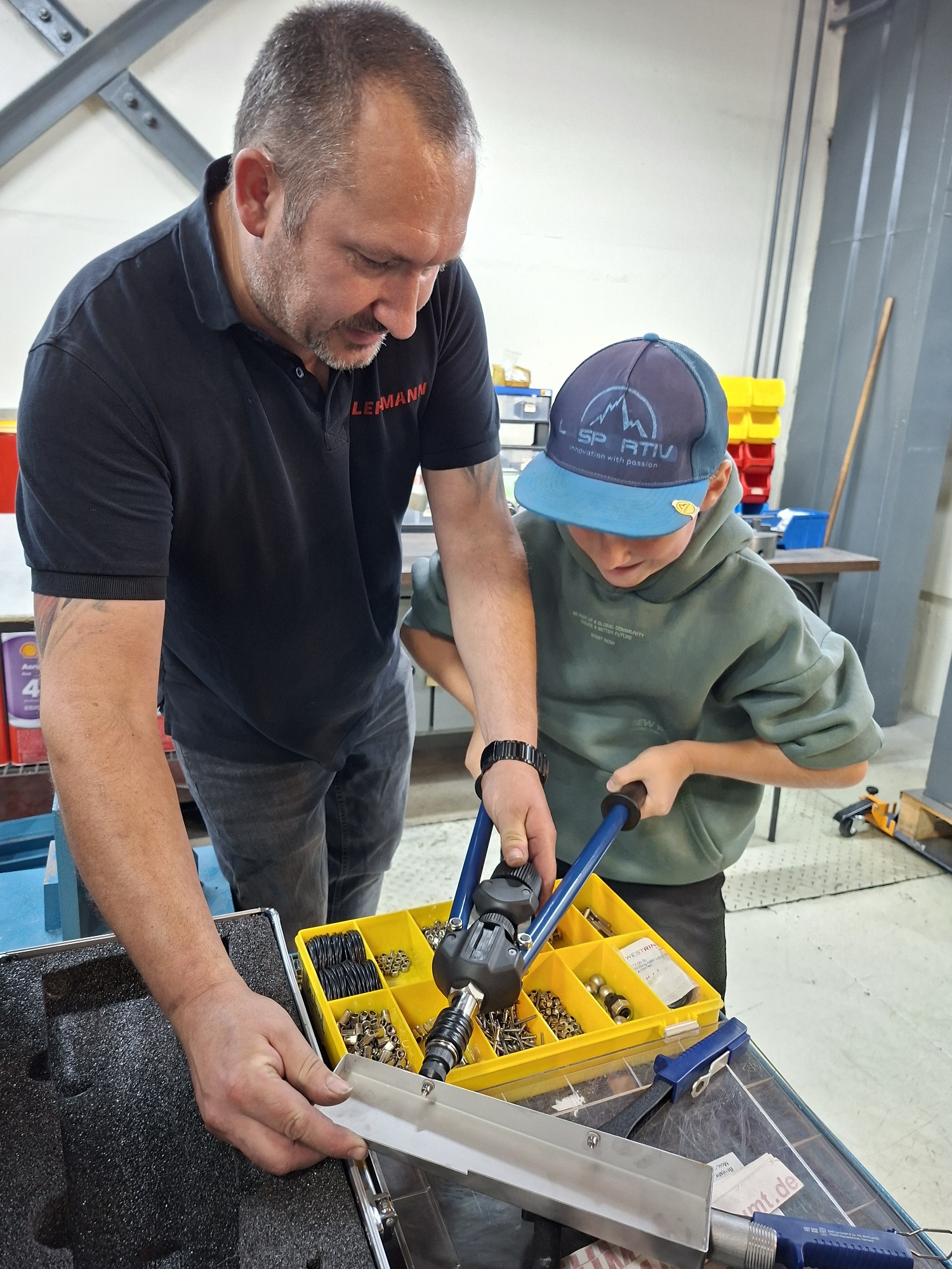 Kind lernt mit Arbeiter die Tätigkeiten bei der Metallbearbeitung kennen